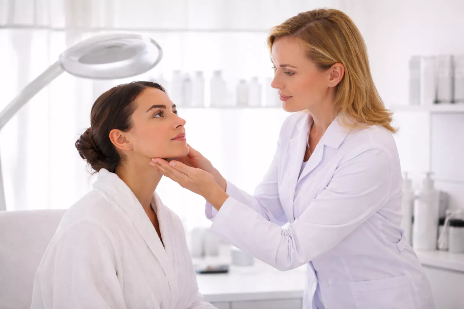 Clinical facial skin assessment during a dermatology consultation showing professional evaluation of pores, congestion, skin texture, oil production, and facial skin health in a medical setting.